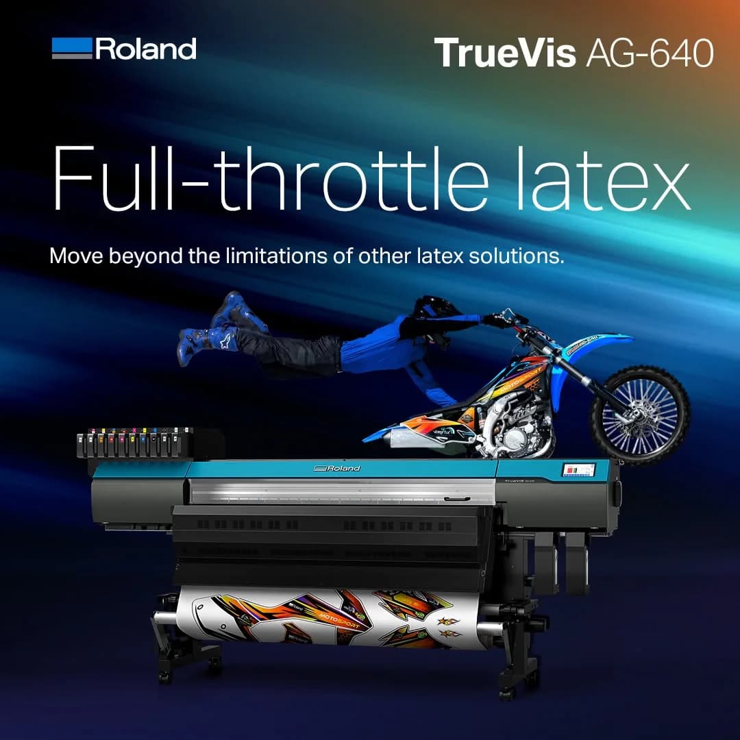Bred rullprinter i turkos och svart som skriver ut motocrossgrafik, ovanför den en förare i luften på en crossmotorcykel