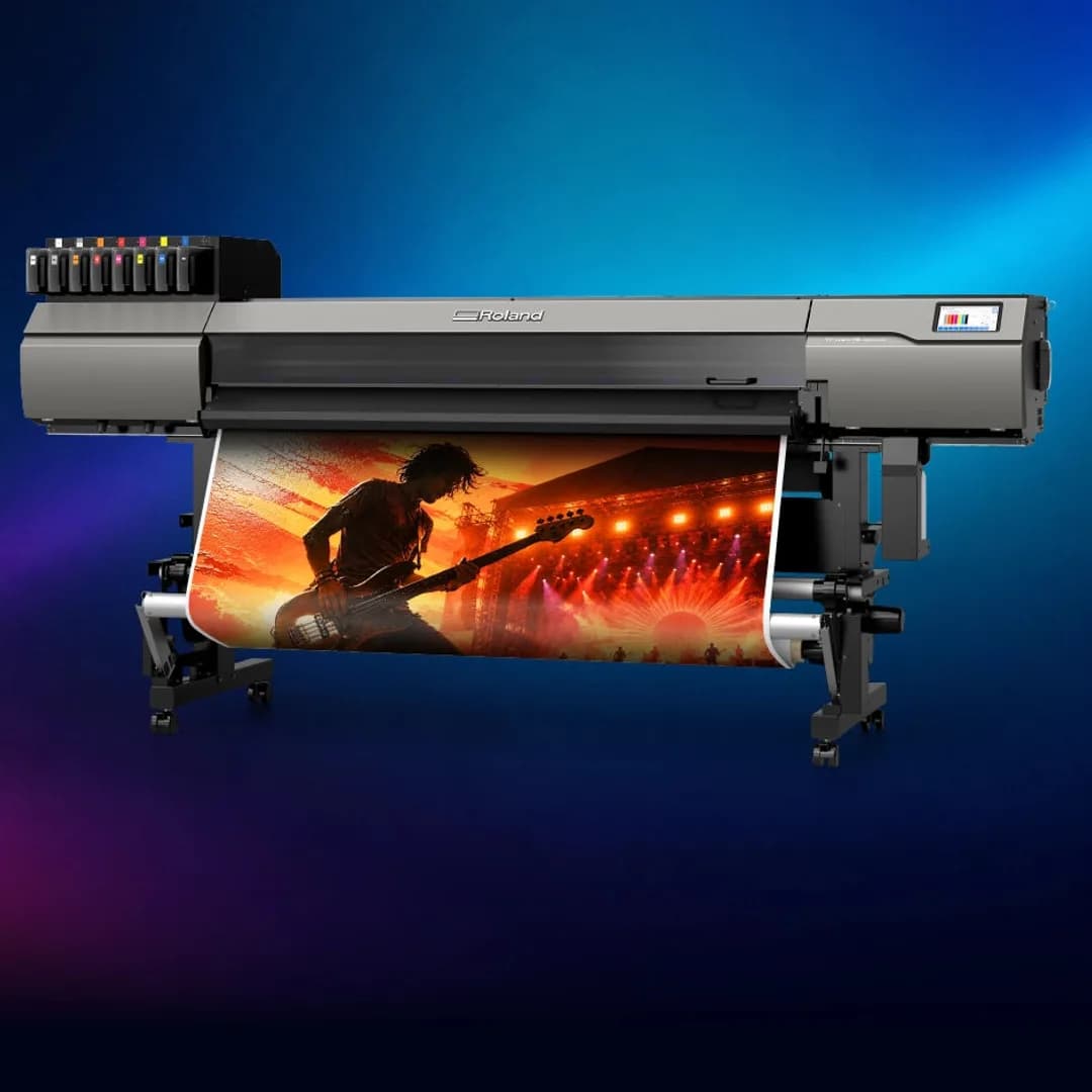 Bred UV-printer i svart och grått som skriver ut en konsertbild i starka färger, mot en bakgrund av blå och röda ljusstråk